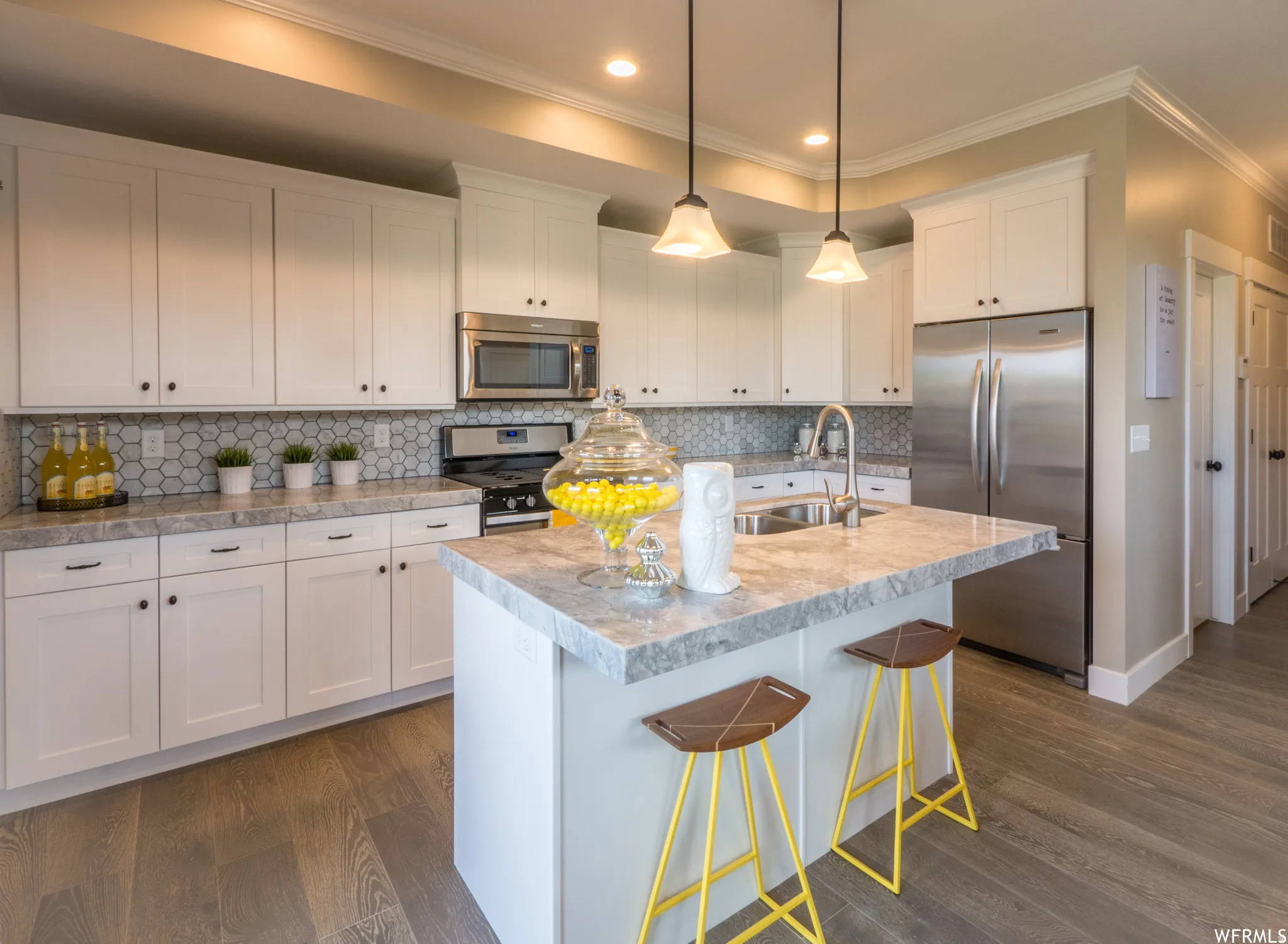 Kitchen featuring white cabinets, stainless steel appliances, tasteful backsplash, light countertops, and crown molding