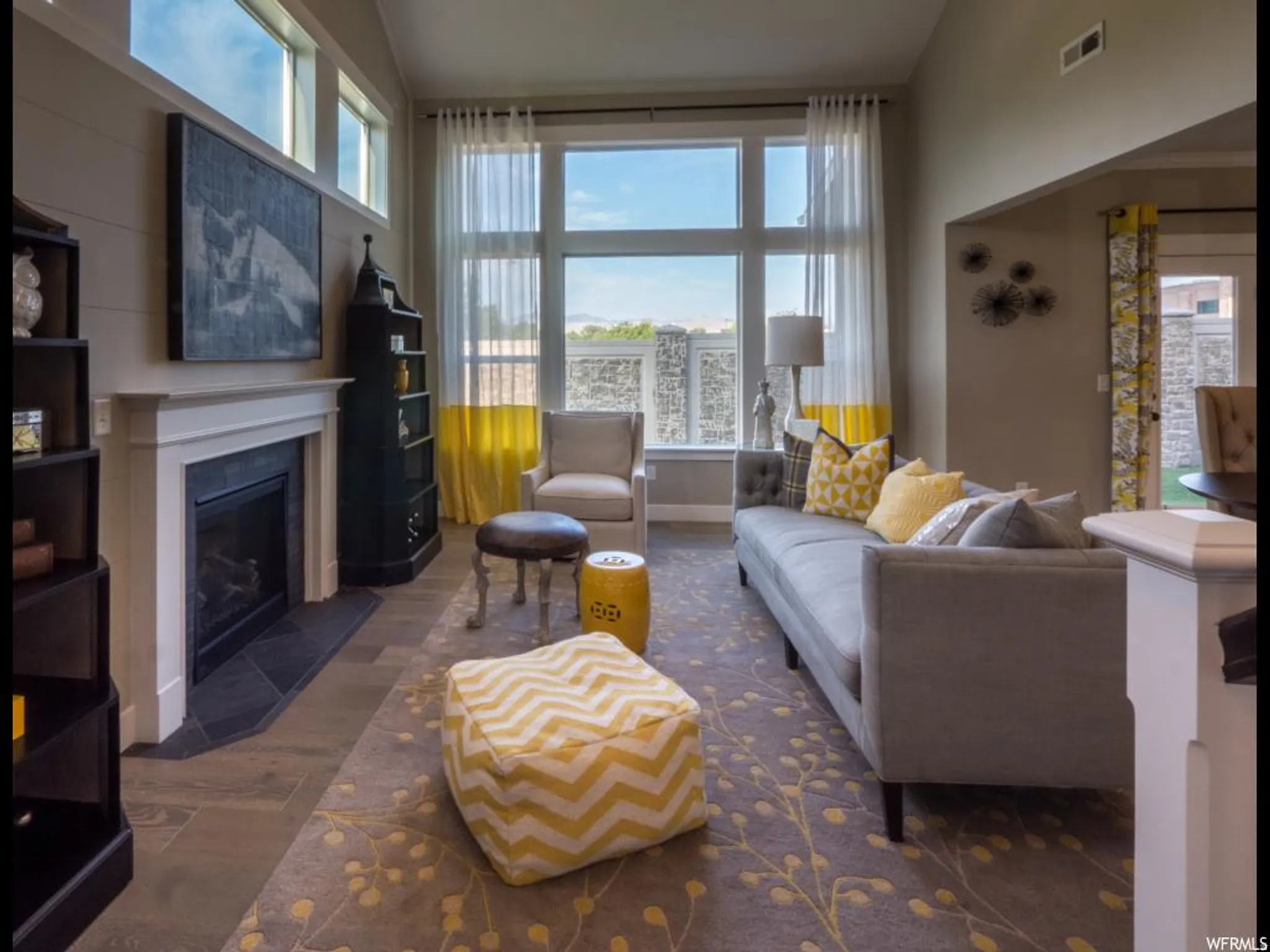 Living room with dark wood-style floors, a glass covered fireplace, plenty of natural light, and lofted ceiling
