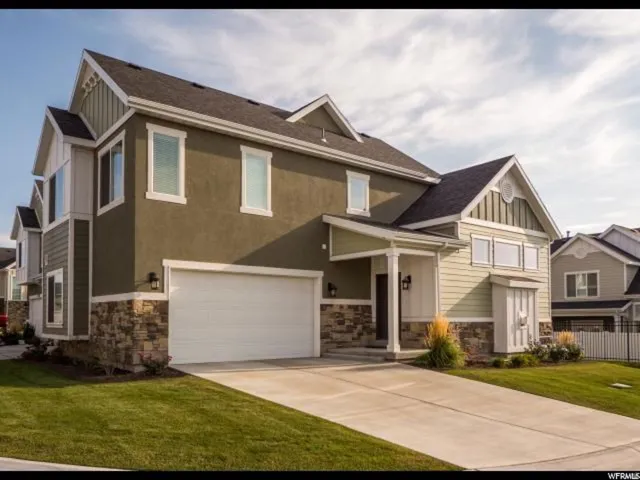 Craftsman inspired home with stone siding, an attached garage, board and batten siding, concrete driveway, and roof with shingles