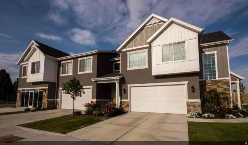 Craftsman-style house featuring stone siding, a garage, concrete driveway, and board and batten siding