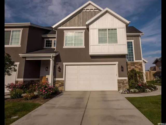 Craftsman-style house featuring stone siding, an attached garage, and driveway