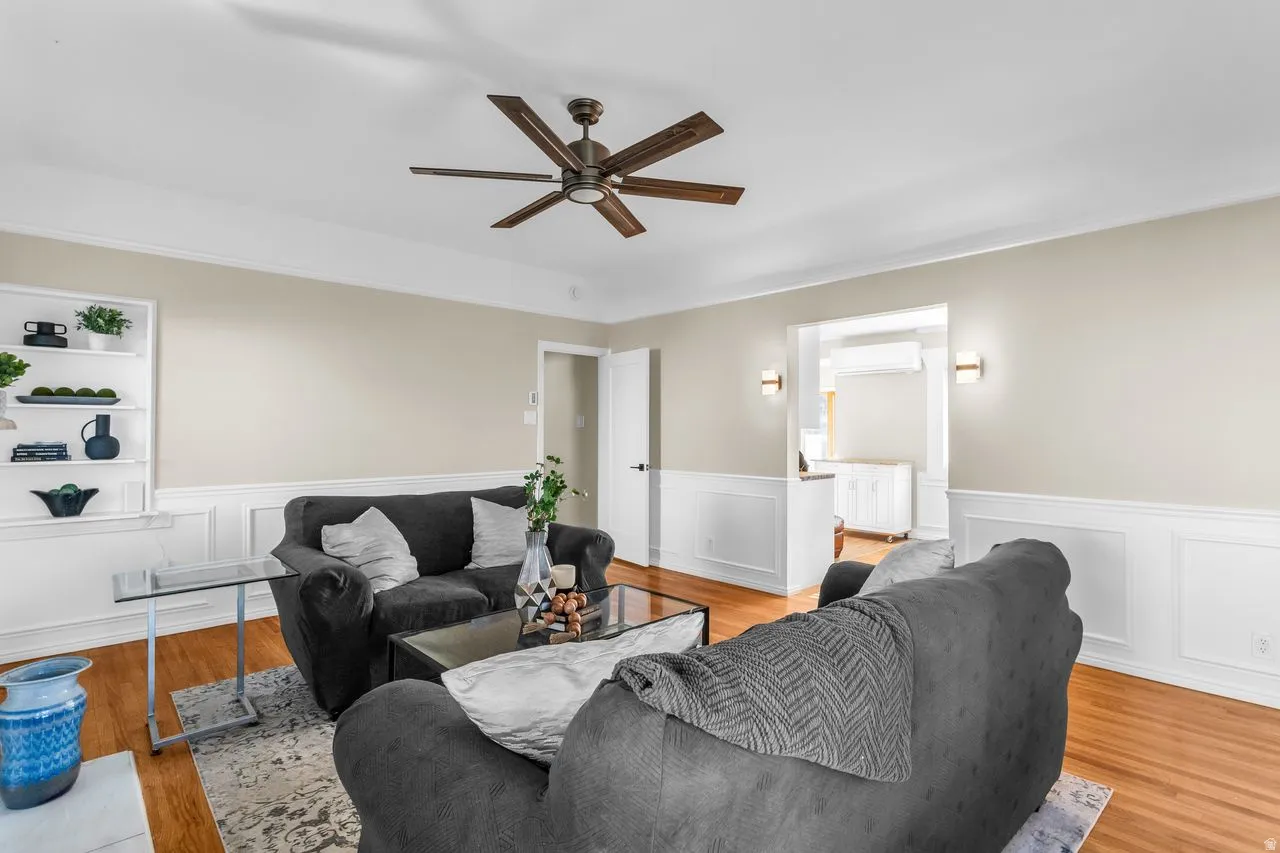 Living space featuring wood-finish flooring, white wainscoting, and recessed built-in shelving