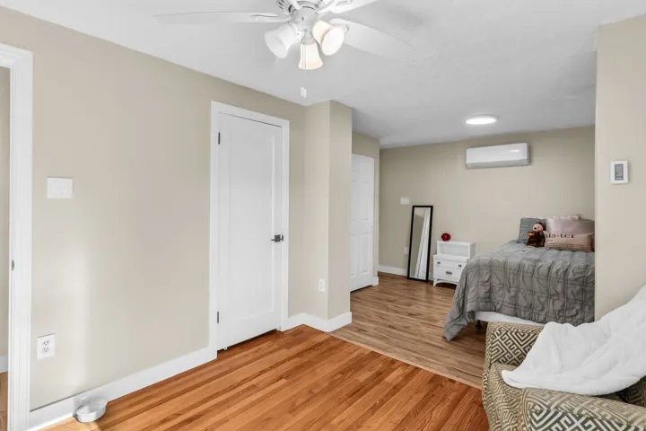 Interior space featuring wood flooring, neutral wall tones, white trim, and a ceiling fan with integrated lighting