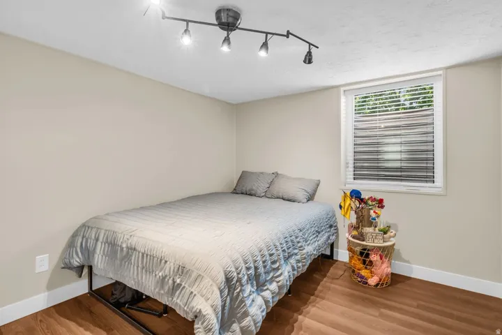 Room featuring wood-finish flooring, a window with blinds, and light-toned walls