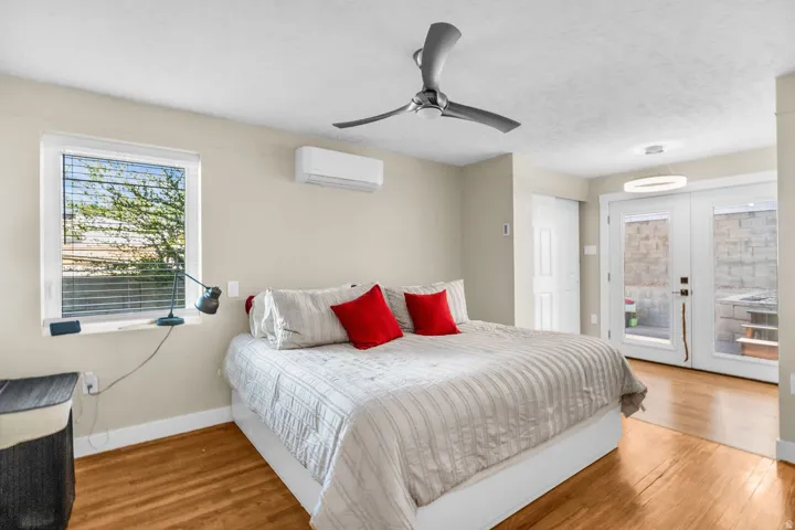 Bedroom featuring wood-finish flooring, a contemporary ceiling fan, and a mini-split HVAC unit