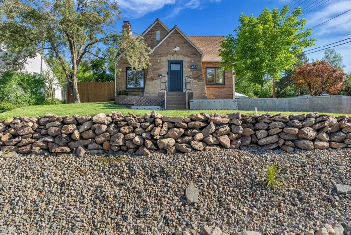 Brick exterior with a prominent stone retaining wall and a gravel-covered slope