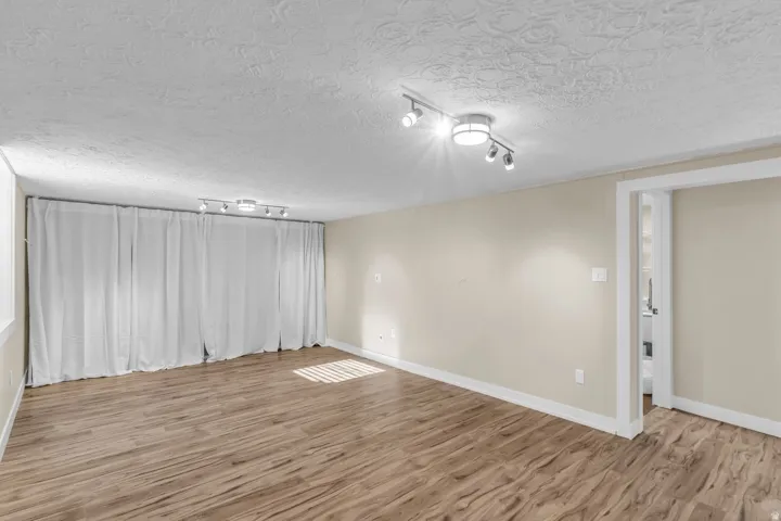 Spacious room featuring wood-finish flooring, light-toned walls, and recessed lighting