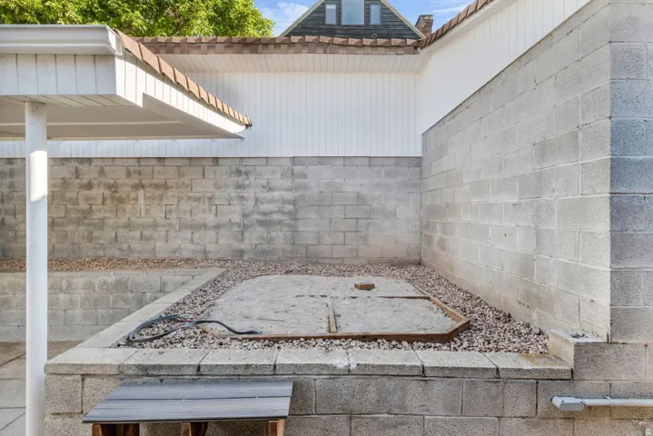 Enclosed outdoor area featuring multiple concrete block retaining walls, a gravel border, and a sand-filled section