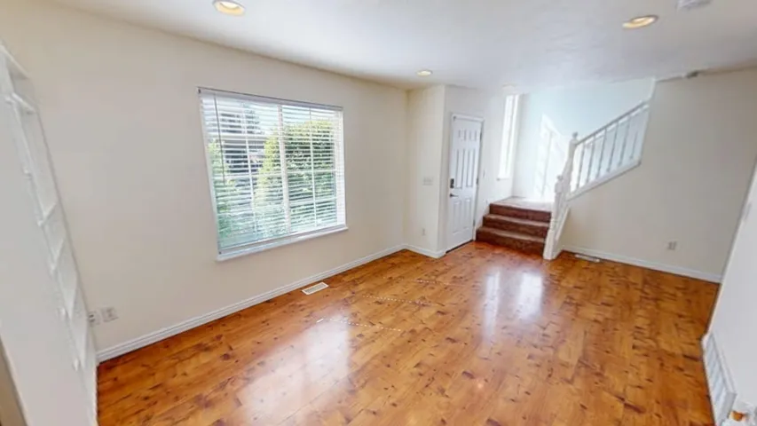 Wood-finish flooring throughout, recessed lighting, and a white paneled door