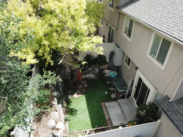 Private backyard featuring a manicured lawn, established trees, and natural rock landscaping