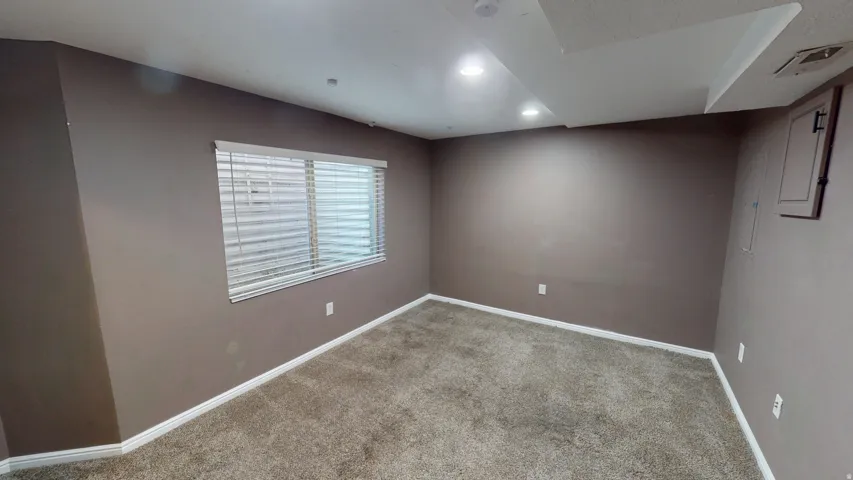 Neutral-toned wall finishes, recessed ceiling lighting, textured carpet flooring, and window with horizontal blinds