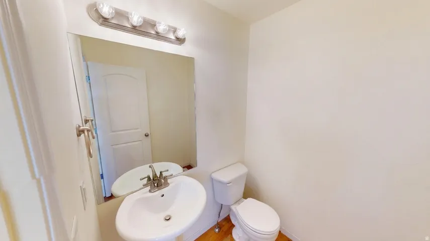 Pedestal sink with a polished chrome faucet, rectangular mirror, and a four-bulb vanity light fixture