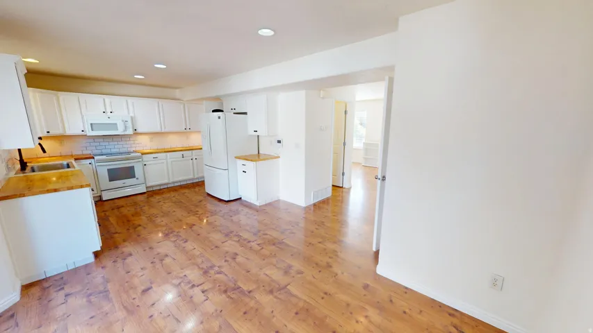Kitchen featuring extensive white cabinetry, wood-finish countertops, stainless steel appliances, and wood-finish flooring