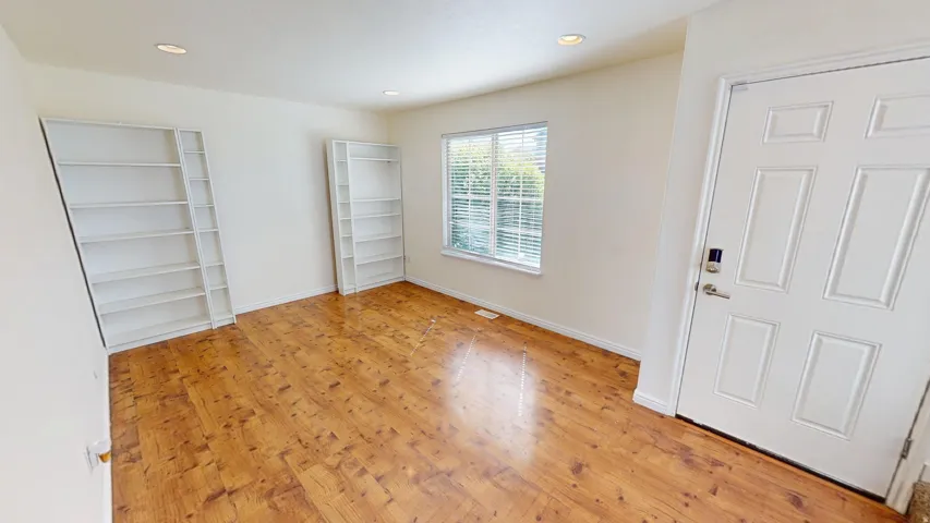 Wood-finish flooring, recessed lighting, built-in shelving, and a multi-pane window with blinds