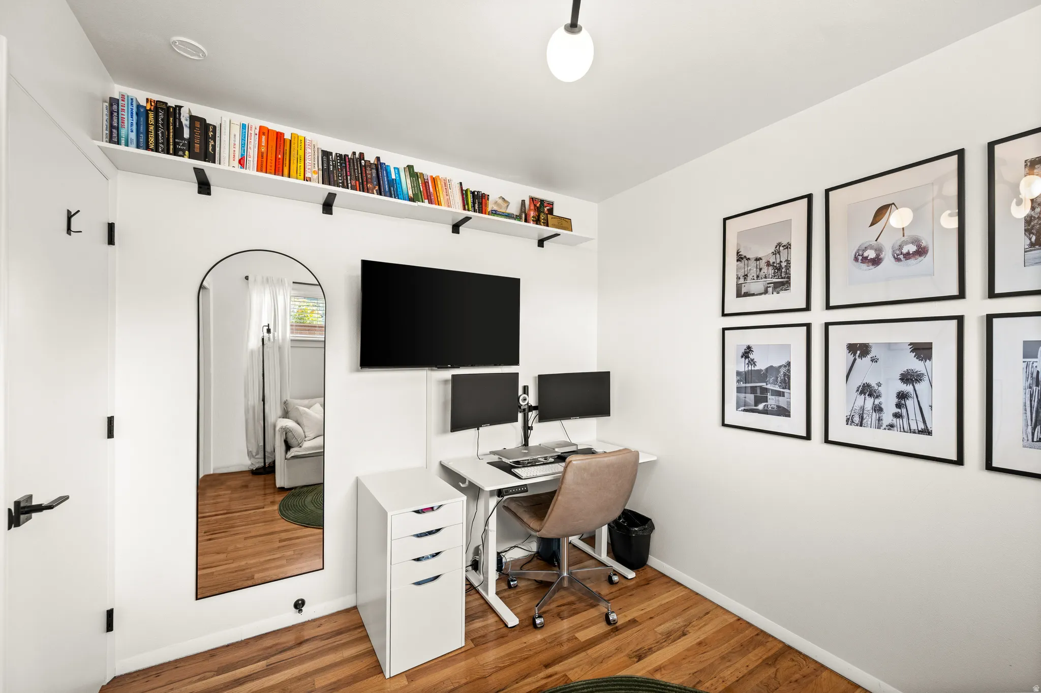 Room featuring wood-finish flooring, white walls, and a built-in wall shelf