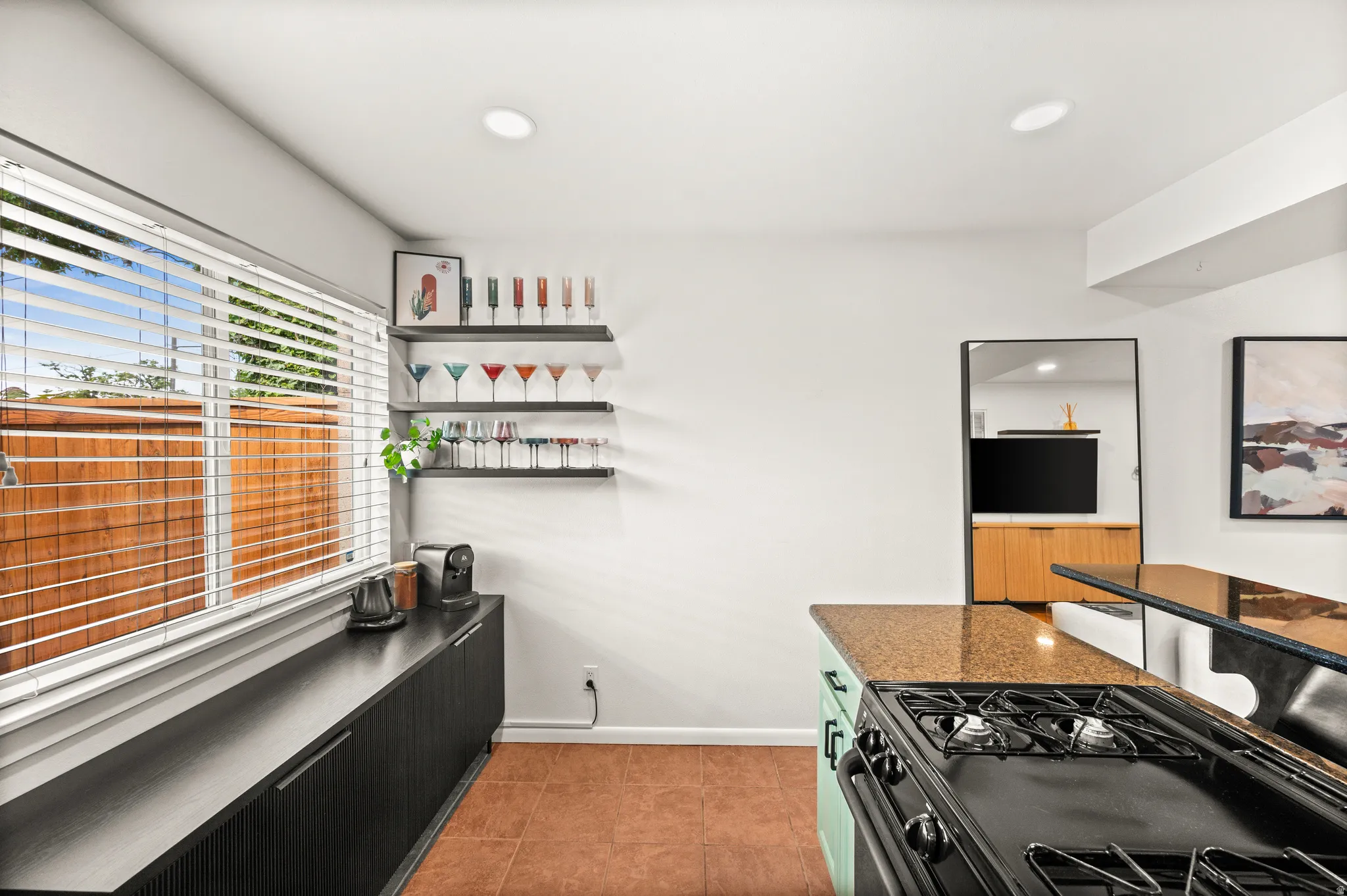 Kitchen area featuring a gas range, a stone-finish countertop, and built-in shelving