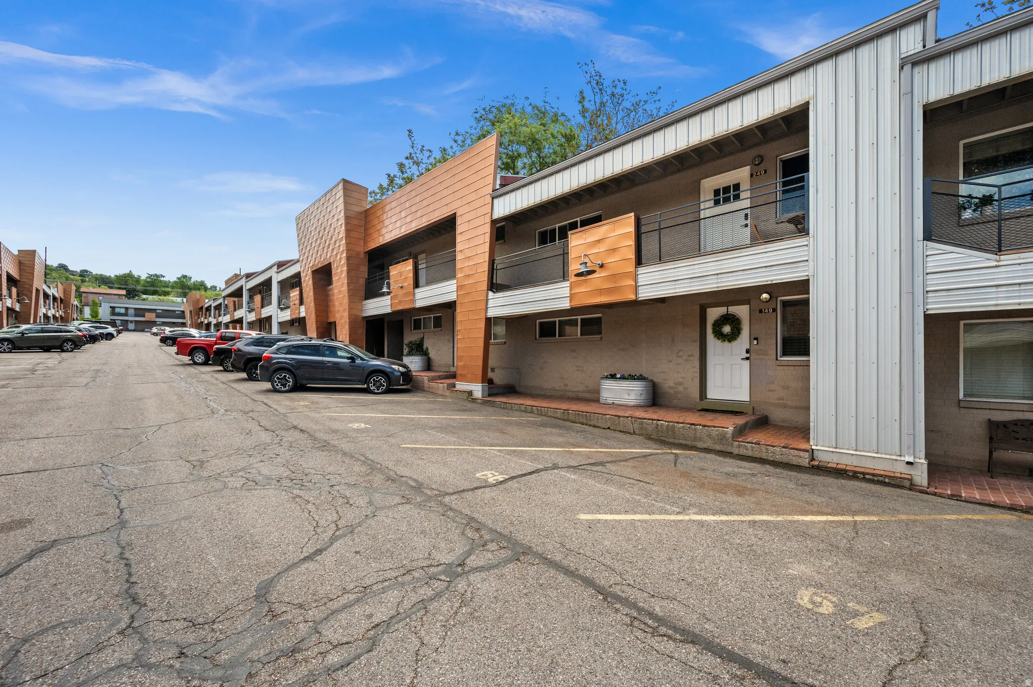 Multi-story residential building featuring a white entry door, brick entryway, and a balcony with metal railings