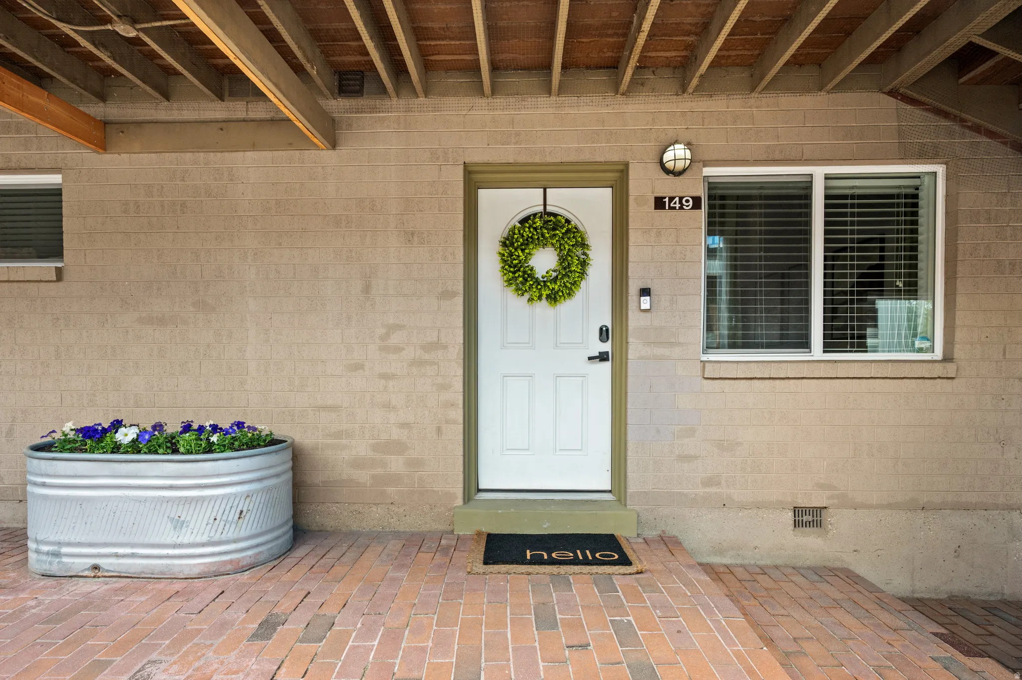 Brick veneer exterior with a white entry door, complemented by a recessed light fixture and a multi-pane window featuring blinds