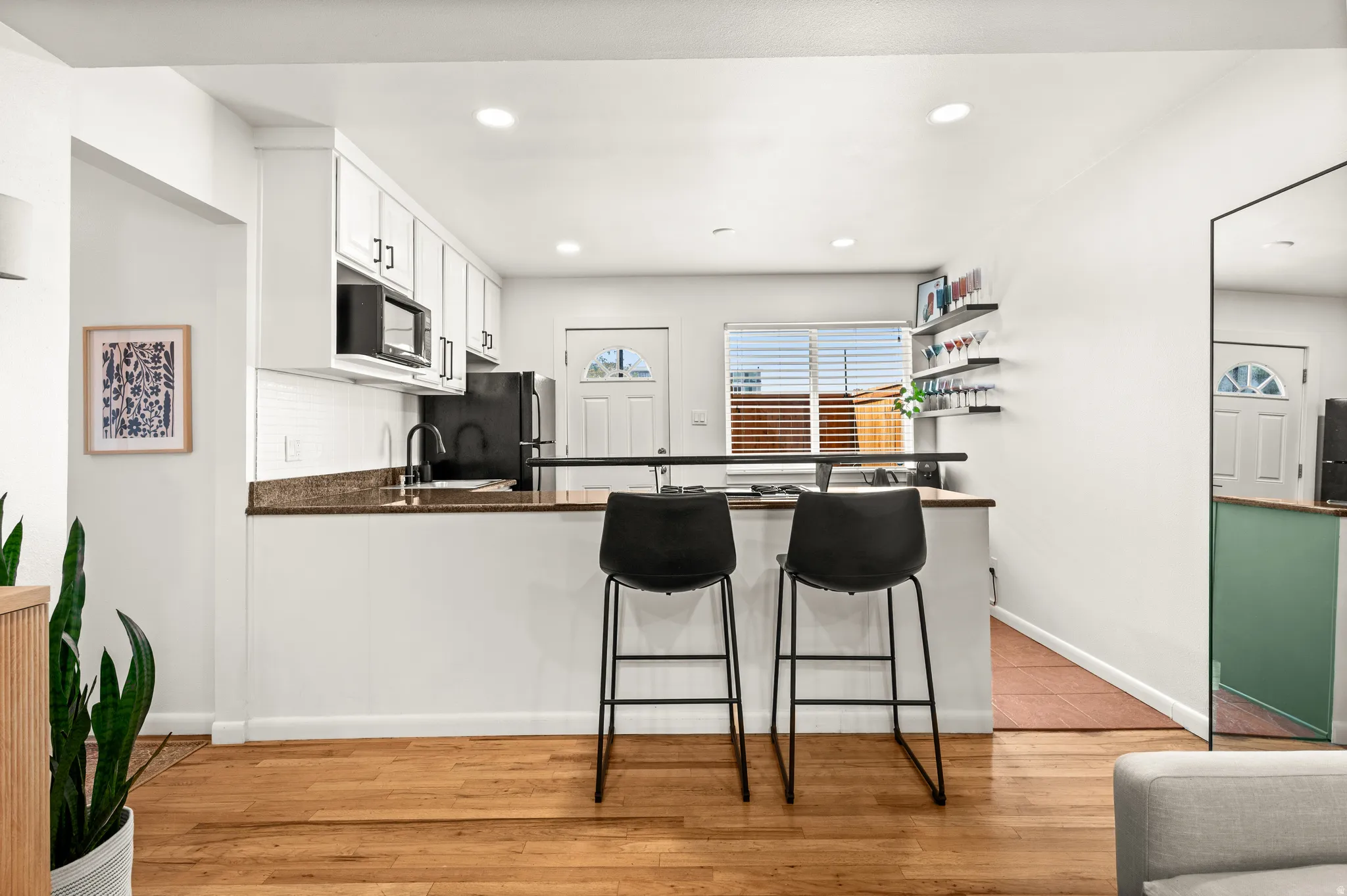 Kitchen featuring white cabinetry, a built-in microwave, dark countertops, and a white subway tile backsplash