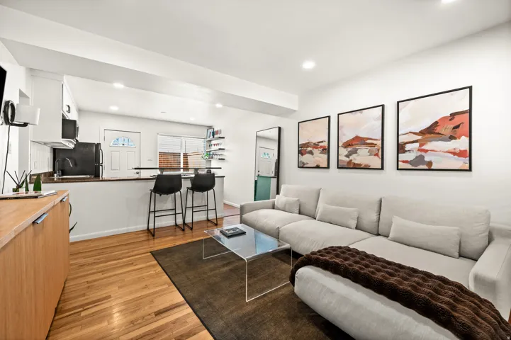 Living area featuring wood-finish flooring, recessed lighting, and a kitchen pass-through with counter seating