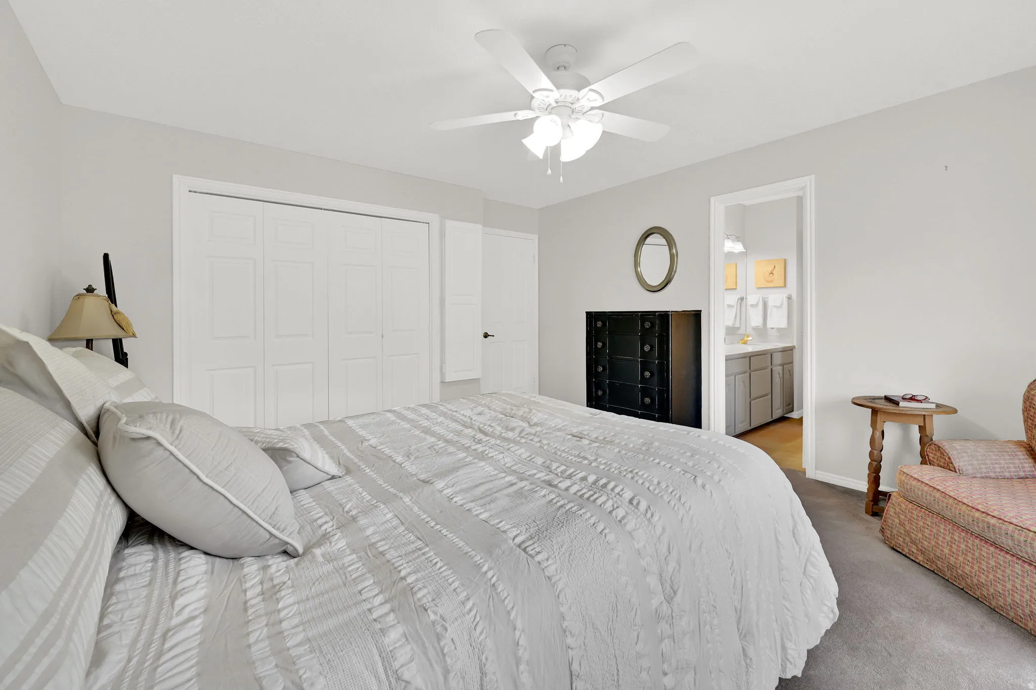Spacious primary bedroom featuring light gray walls and a ceiling fan
