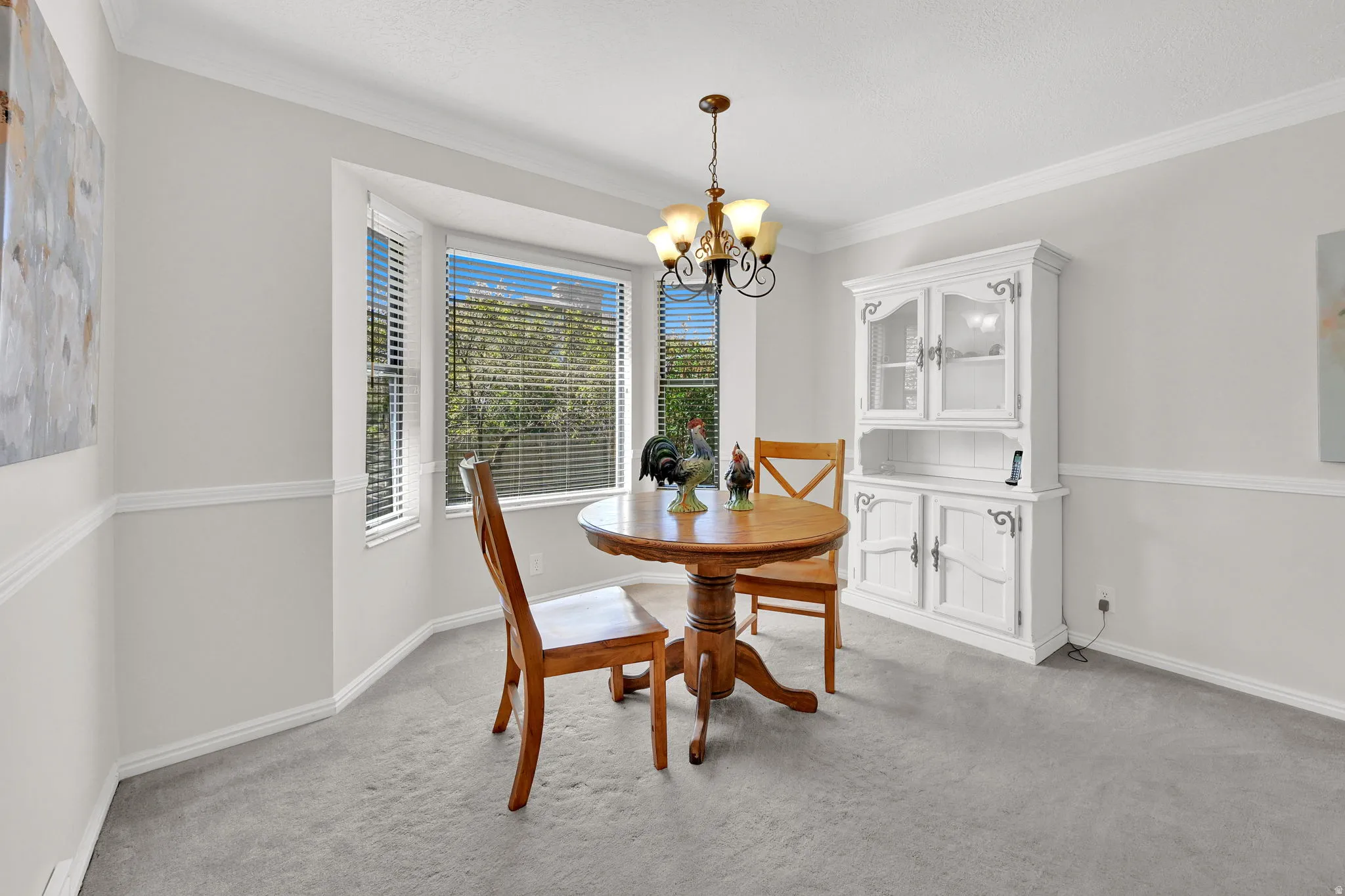 Bay window with horizontal blinds, featuring a chandelier light fixture