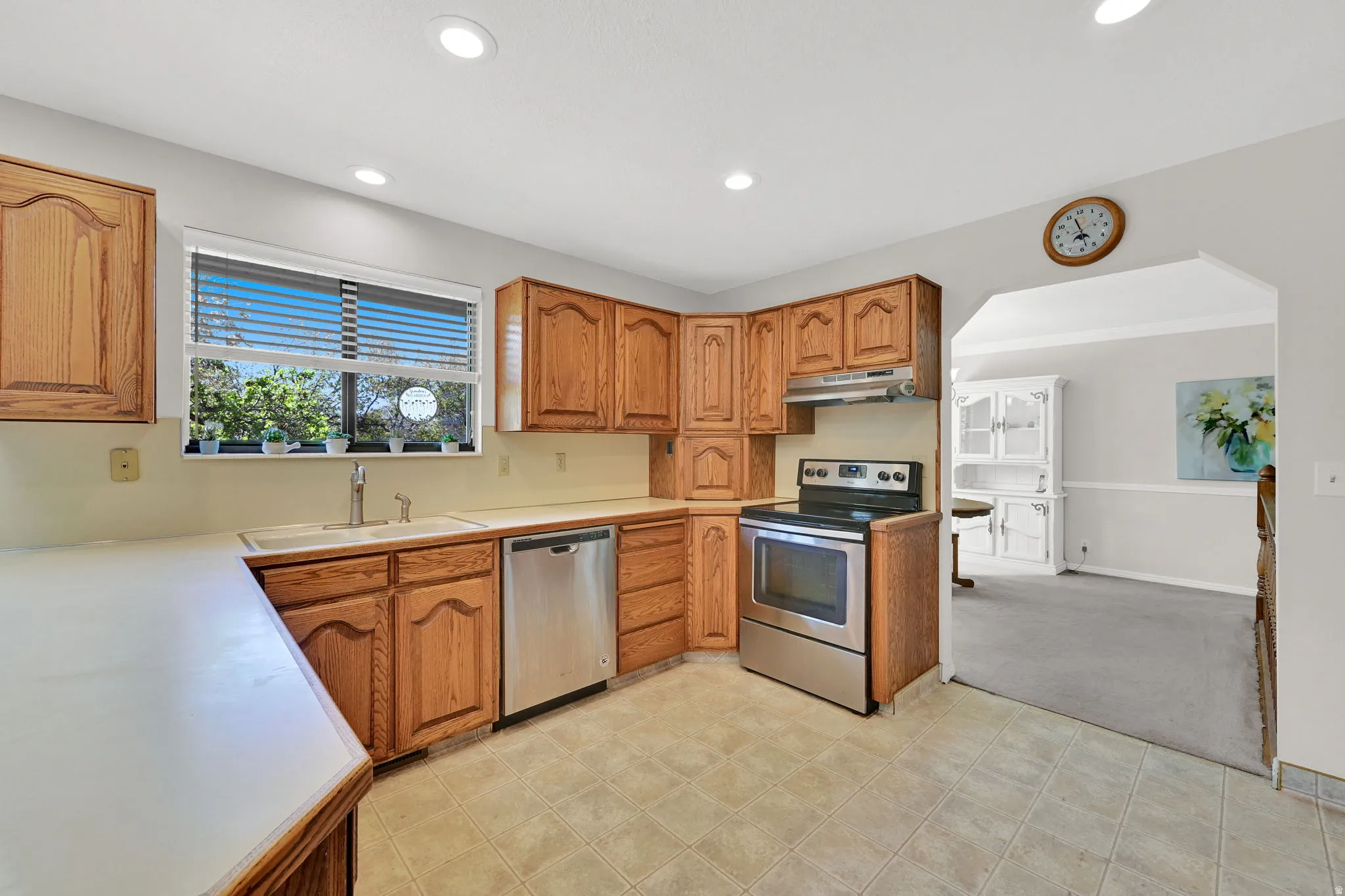 Kitchen featuring oak cabinetry, tile flooring, and stainless steel appliances, including a range and dishwasher