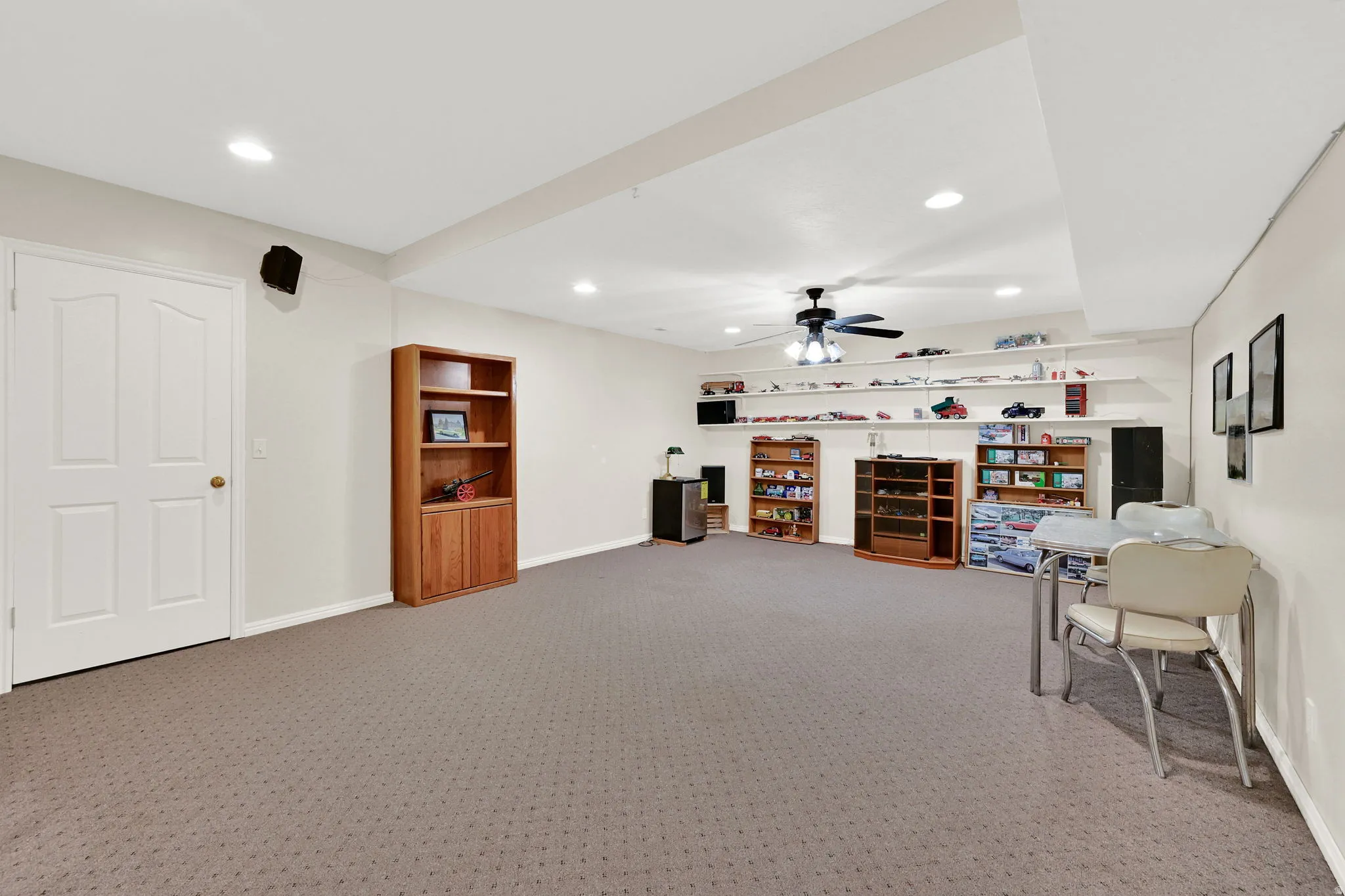 Spacious finished room featuring carpeted flooring, recessed lighting, and a ceiling fan, and access to cold storage room.