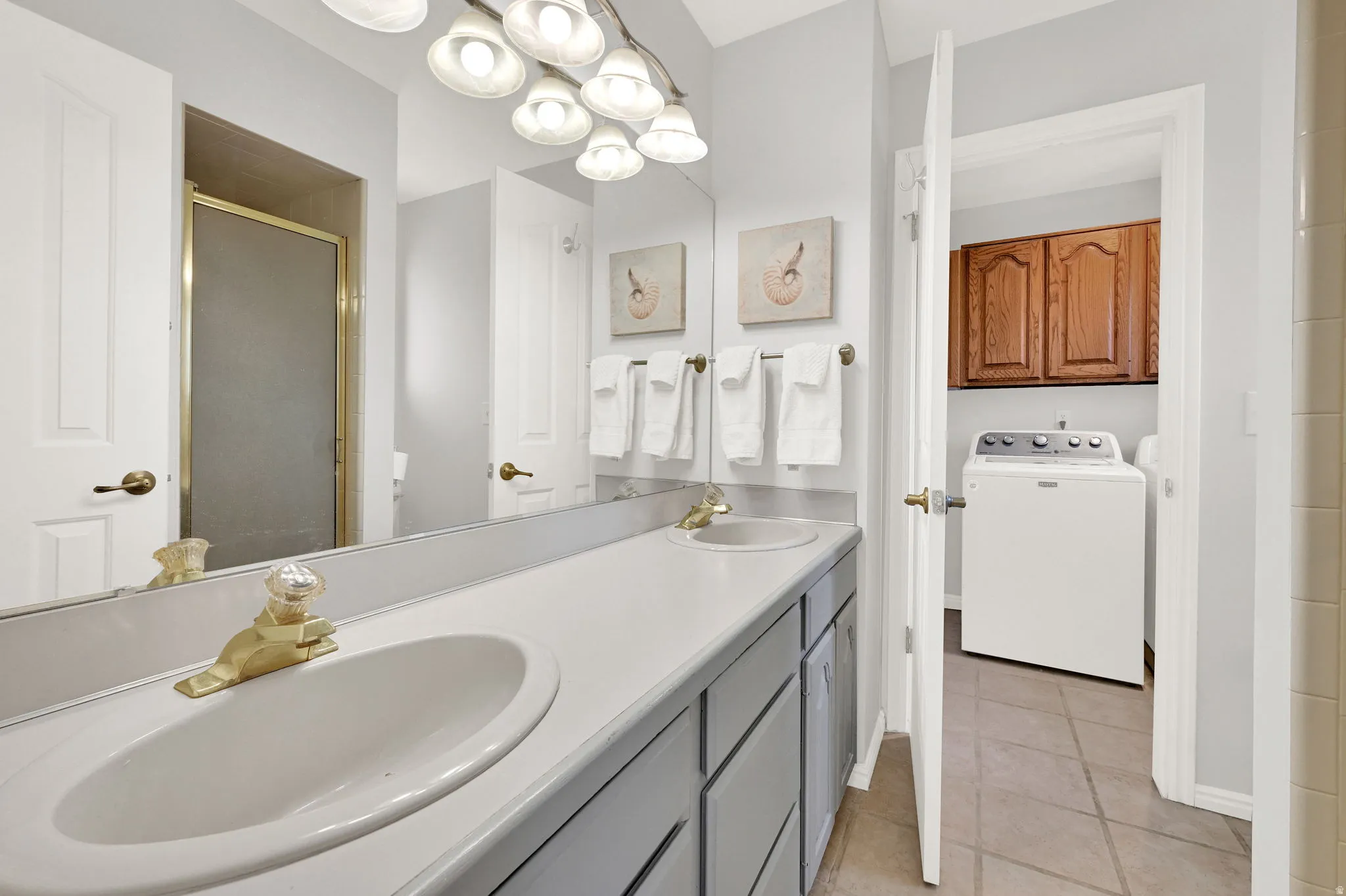Primary bathroom with dual vanity featuring integrated sinks, a lengthy mirror, and overhead decorative lighting