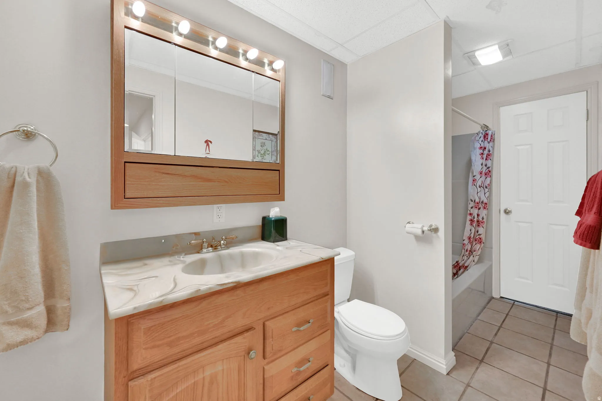 Bathroom featuring a light wood vanity with a patterned countertop and an undermount sink