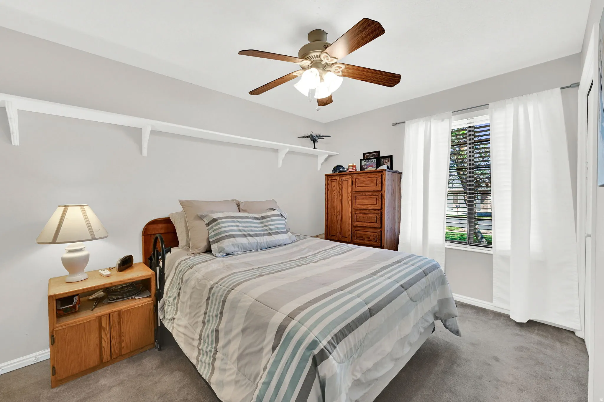 Carpeted bedroom #2 featuring a ceiling fan with integrated lighting, a window with blinds and curtain rod, and light-toned wall paint