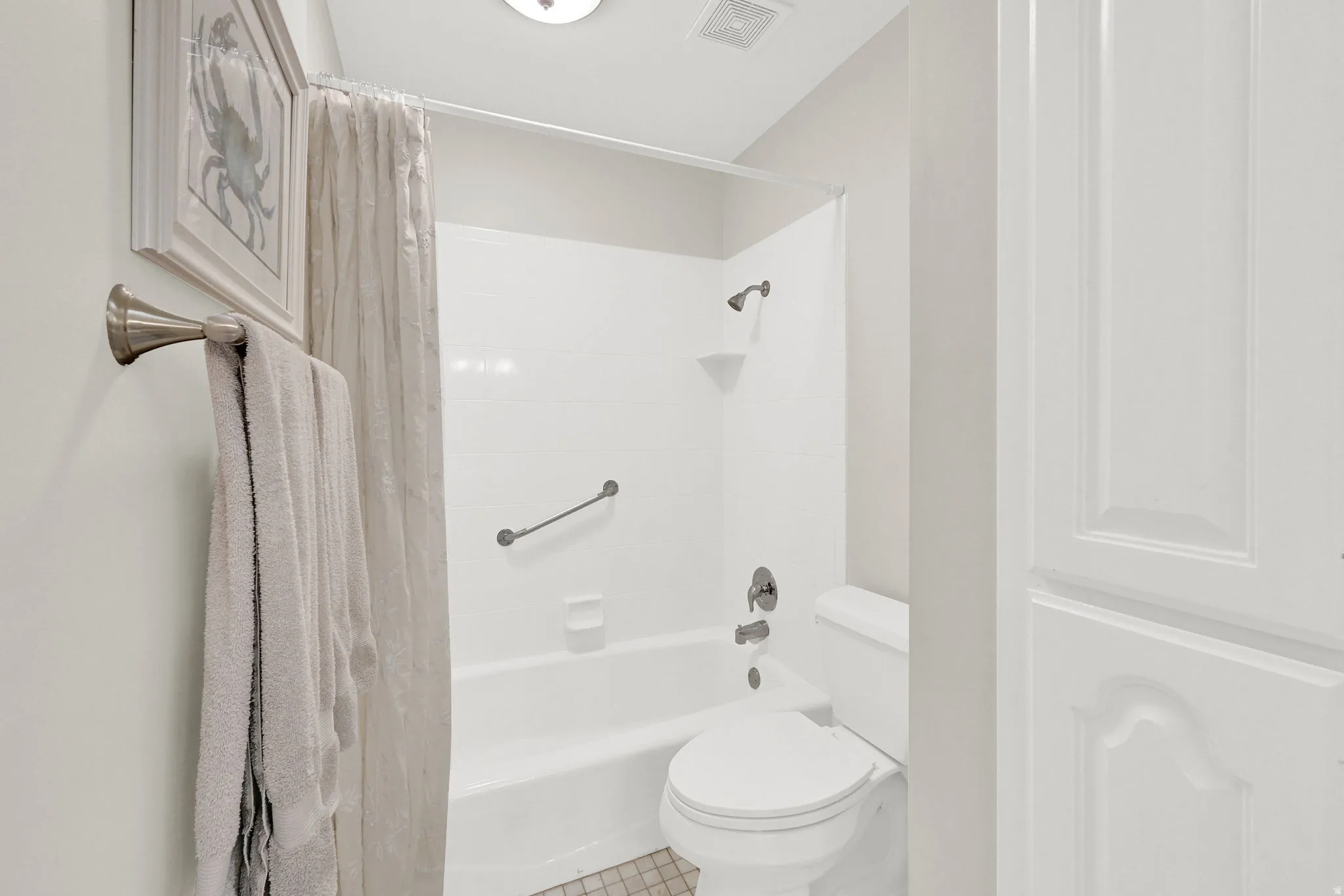 Full bathroom featuring a white tub/shower combination, brushed nickel fixtures, and a white toilet