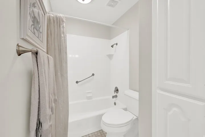 Full bathroom featuring a white tub/shower combination, brushed nickel fixtures, and a white toilet