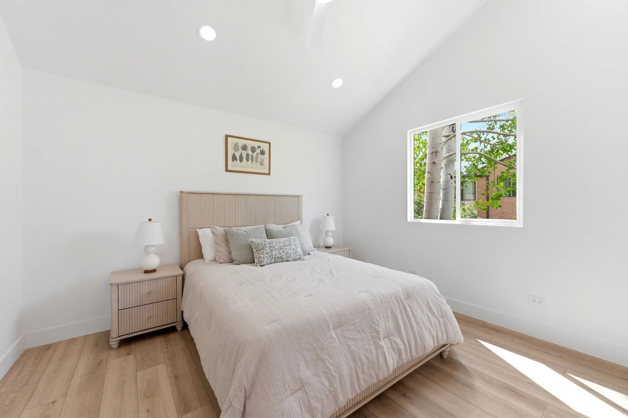 Vaulted ceilings with recessed lighting, wood-finish flooring, and a large window