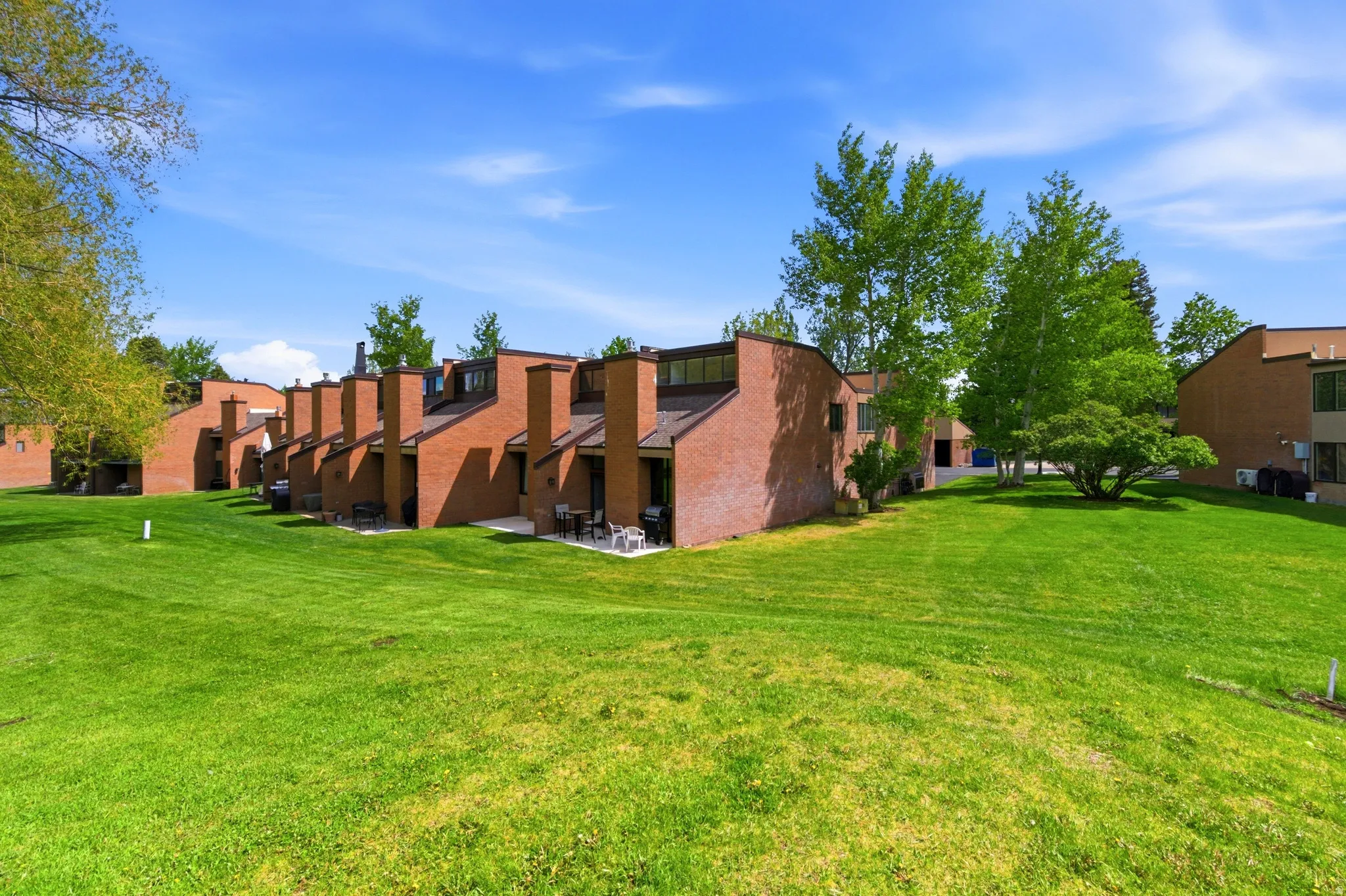 Expansive green lawn bordering a row of brick-clad townhomes