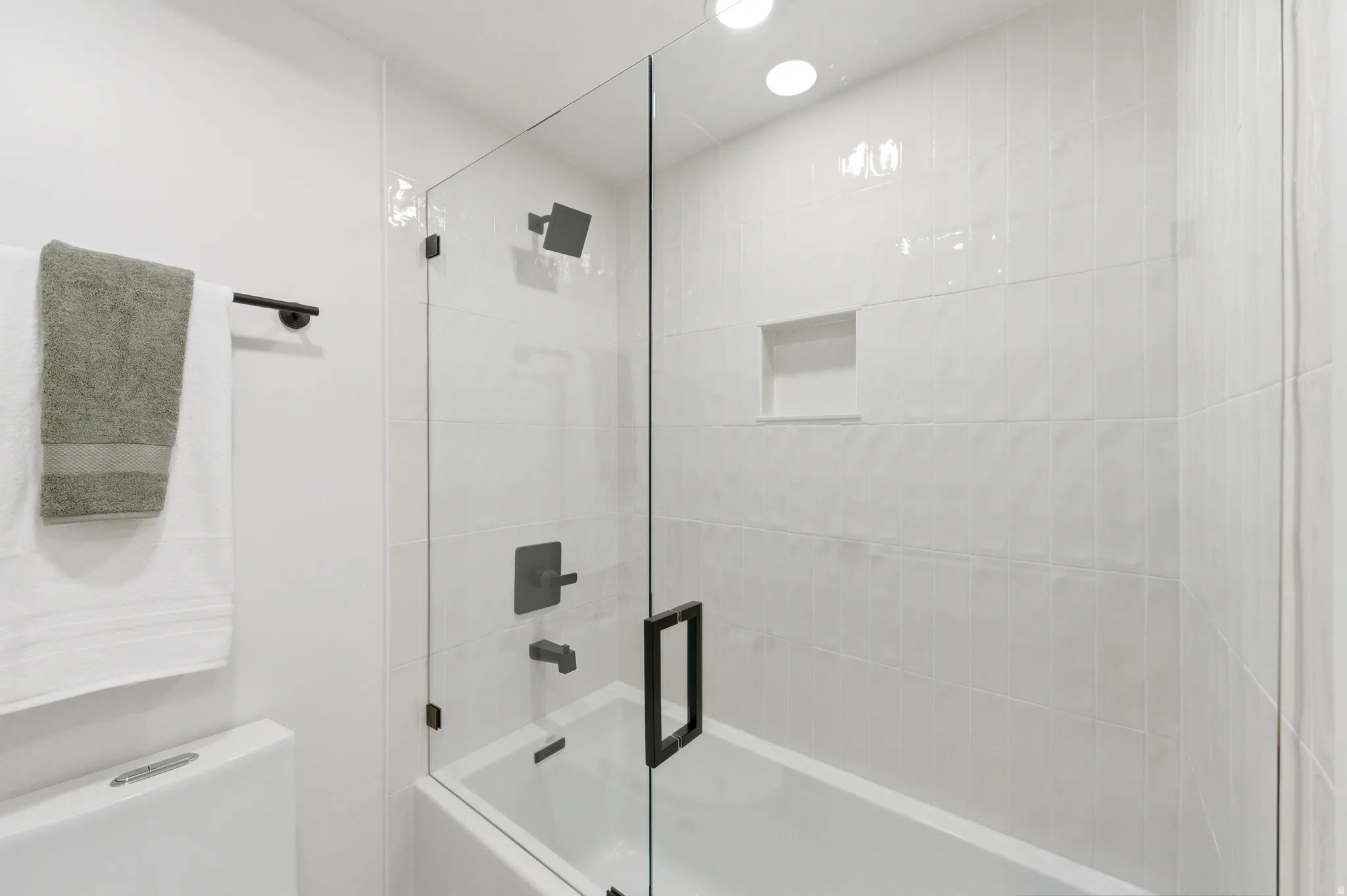 Full bathroom featuring a tub-shower combination with a frameless glass enclosure