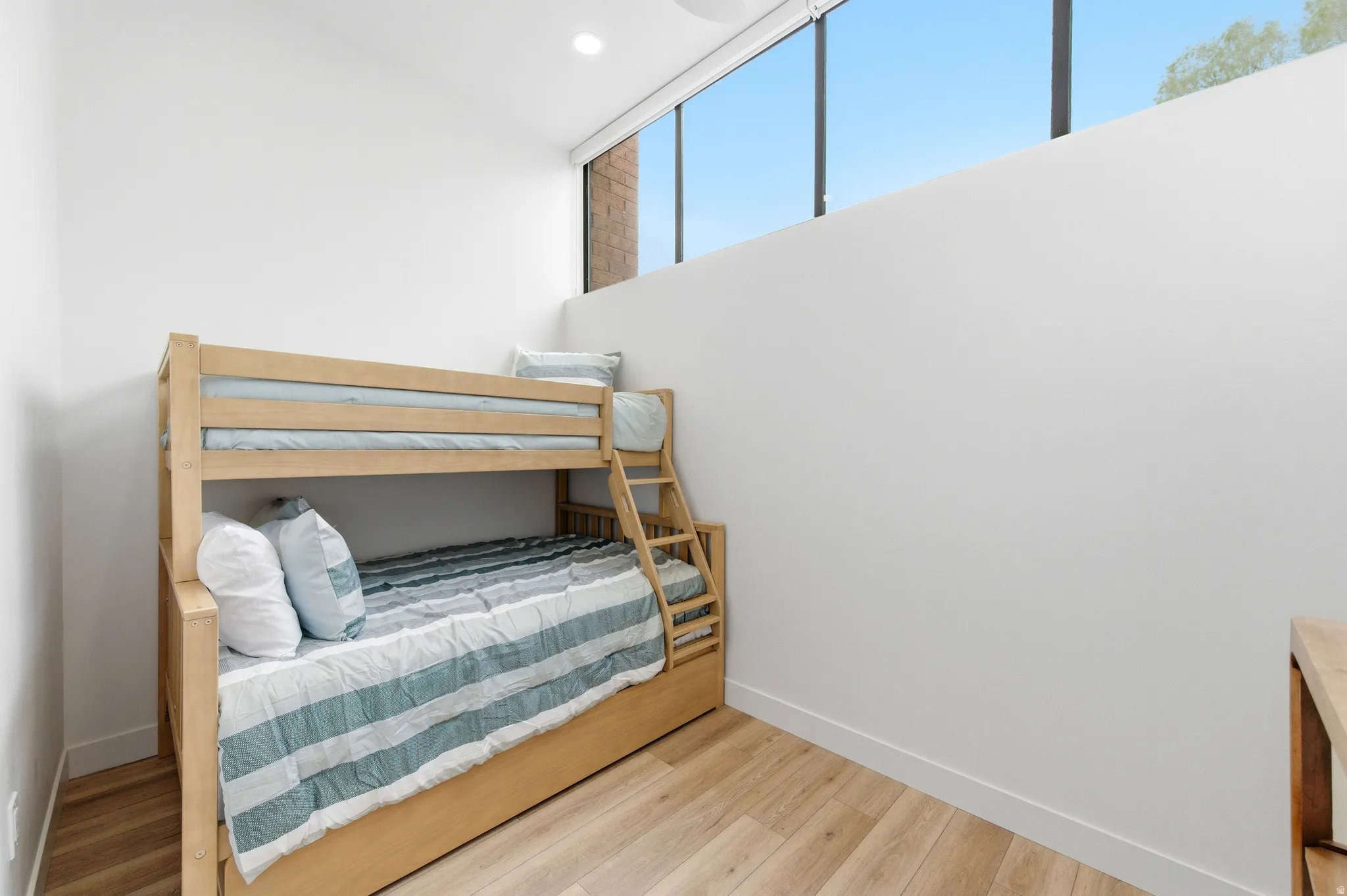 Room featuring light wood-finish flooring, white walls, and a high horizontal window