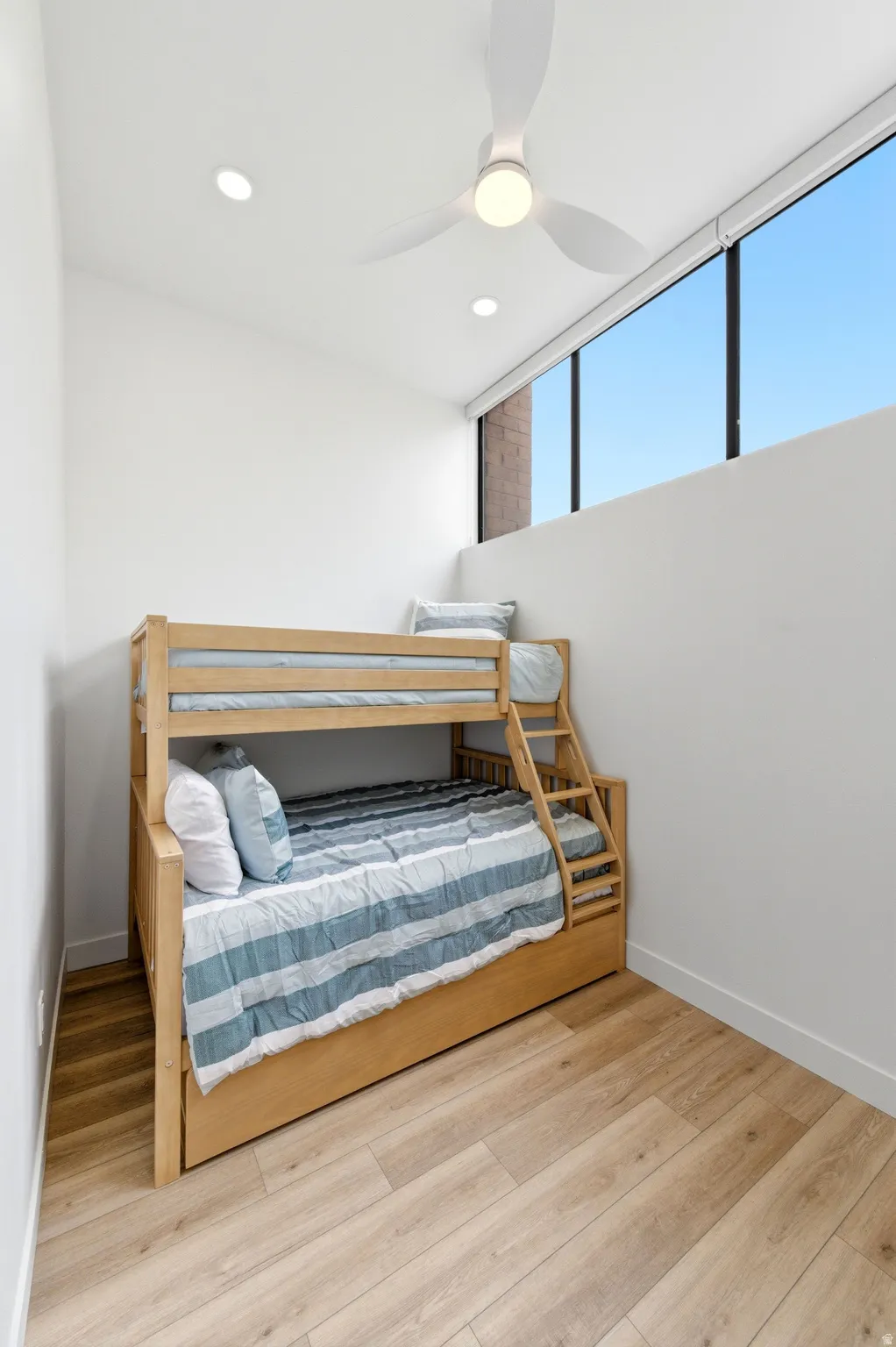 Room featuring high ceilings, wood-finish flooring, a modern ceiling fan, recessed lighting, and expansive upper windows