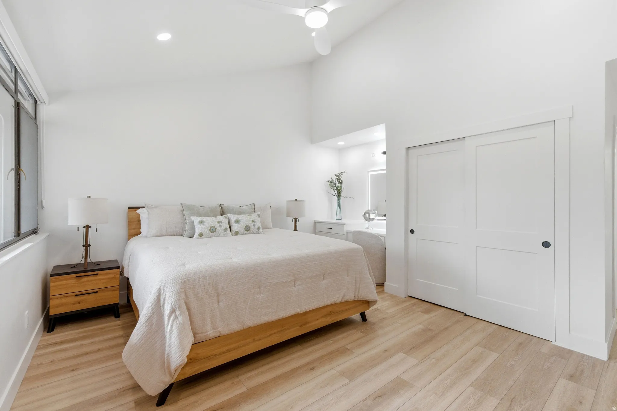 Vaulted ceiling bedroom with light wood-finish flooring