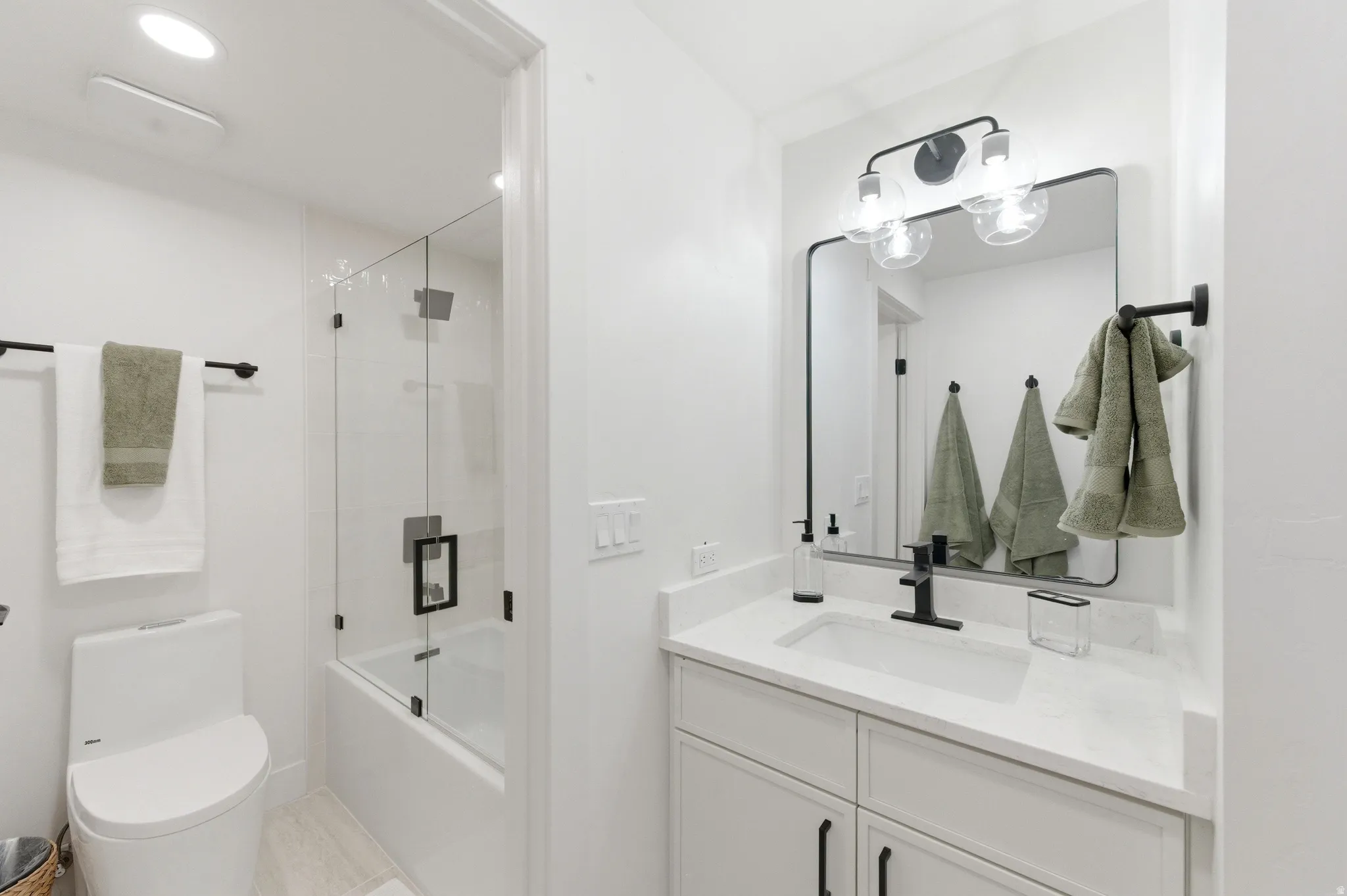 Bathroom featuring a white vanity with an undermount sink, a stone countertop, and matte black fixtures