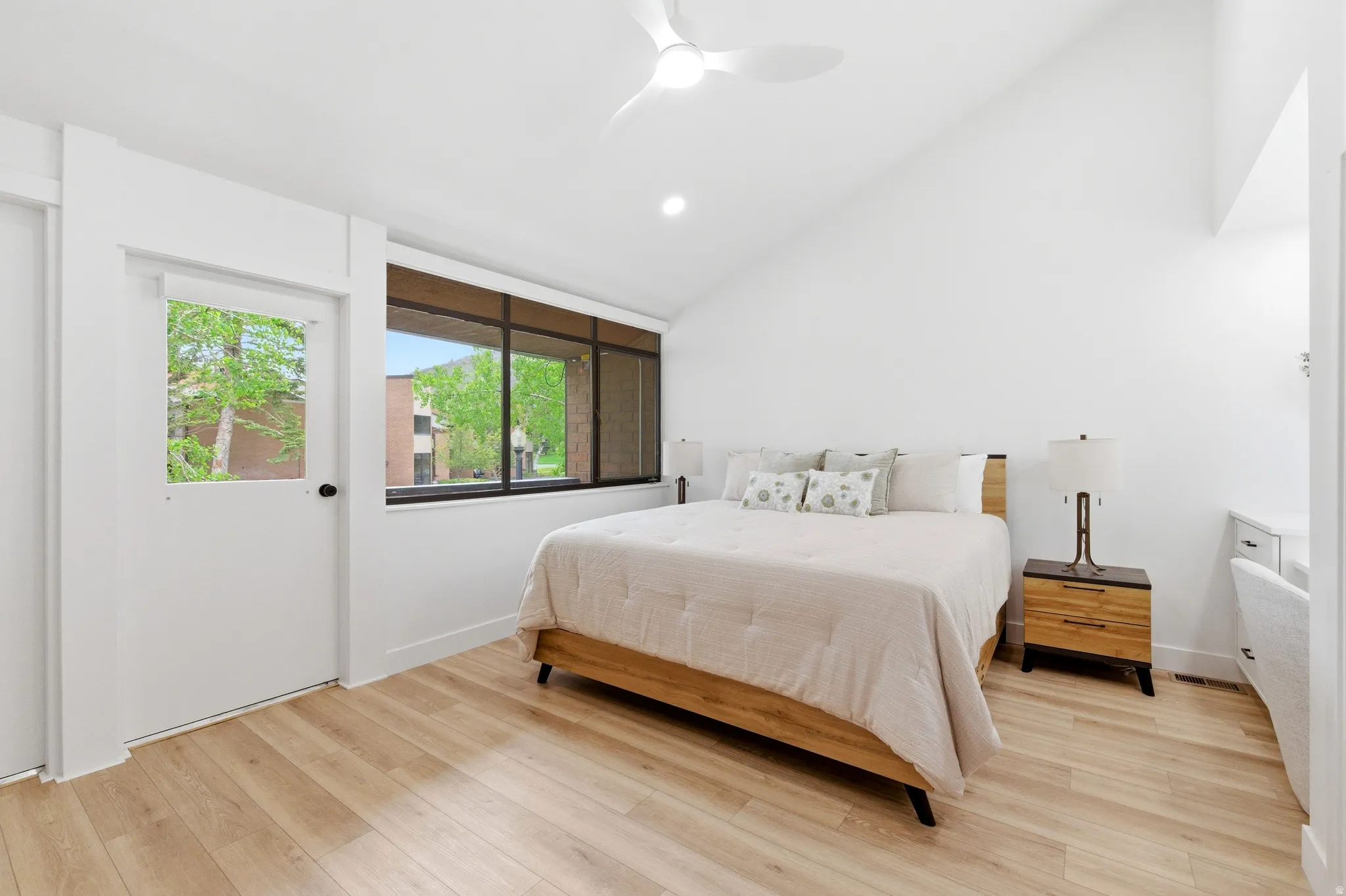 Bright room featuring wood-finish flooring and a white vaulted ceiling with a modern ceiling fan