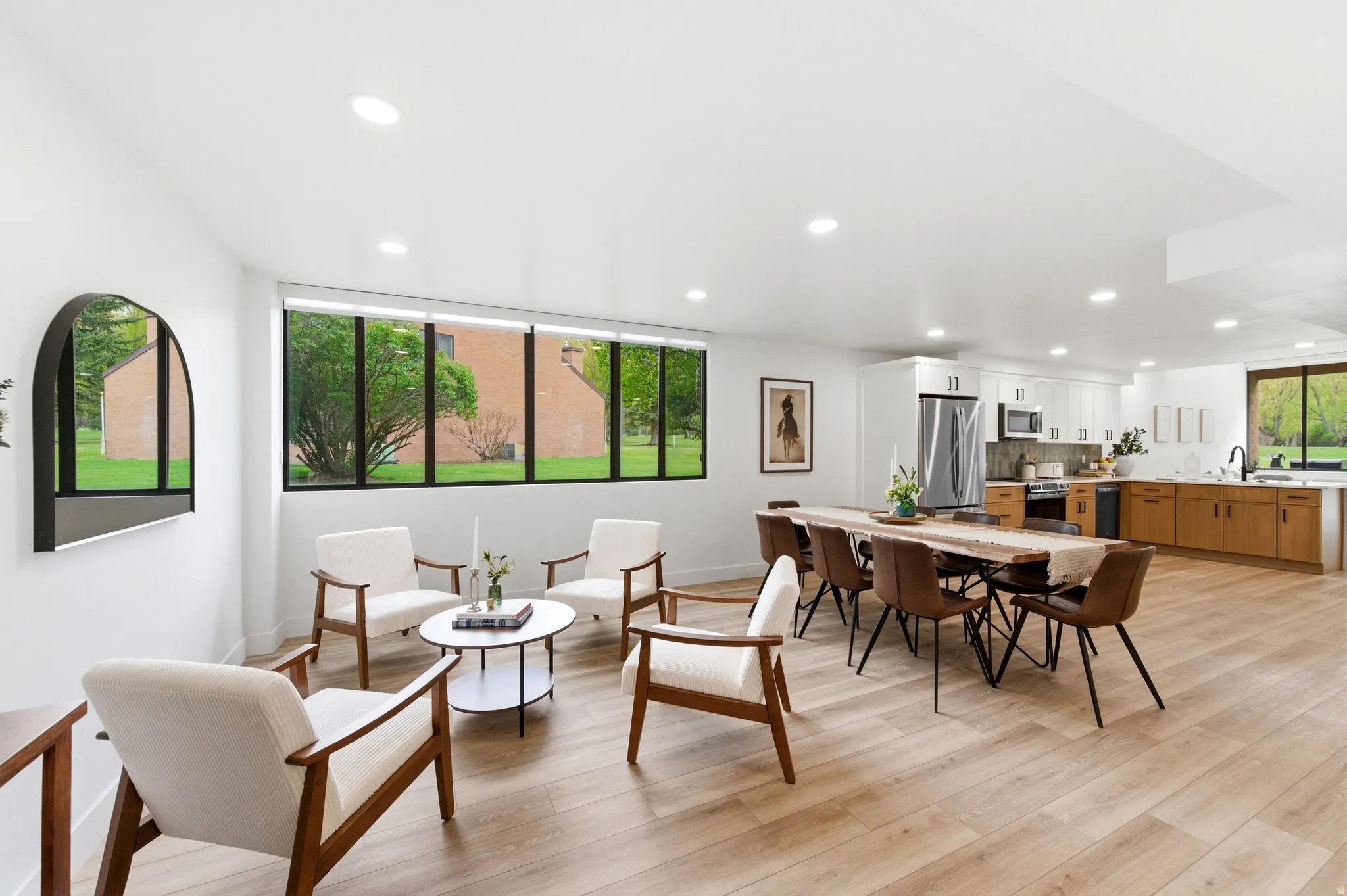 Open-concept living space featuring wood-finish flooring, recessed lighting, and a linear window