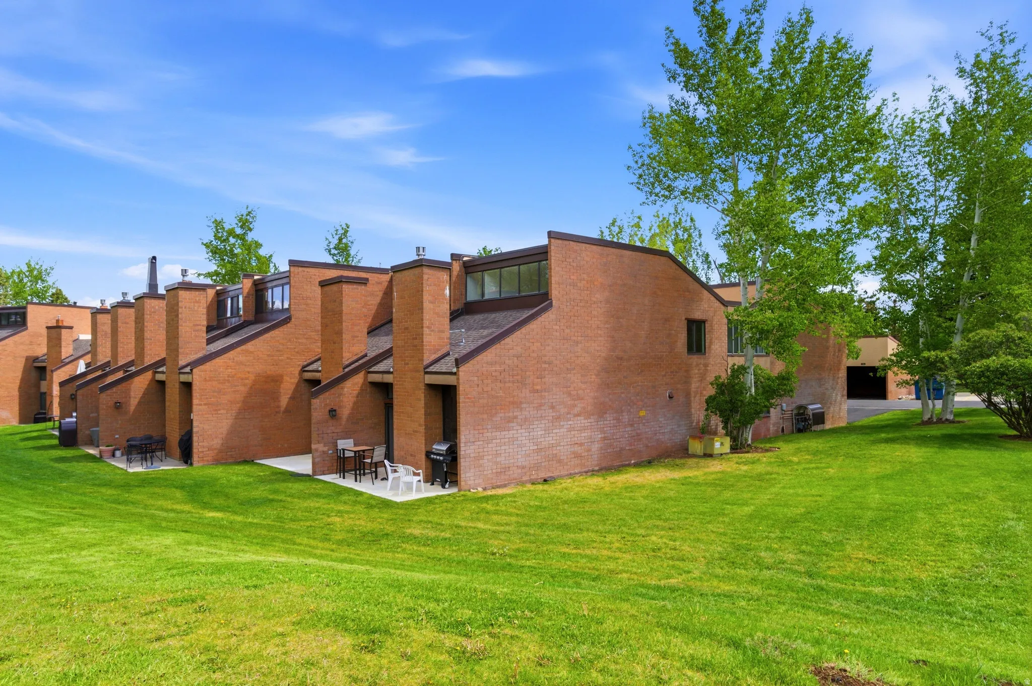 Terraced brick townhomes with pitched roofs and individual patios