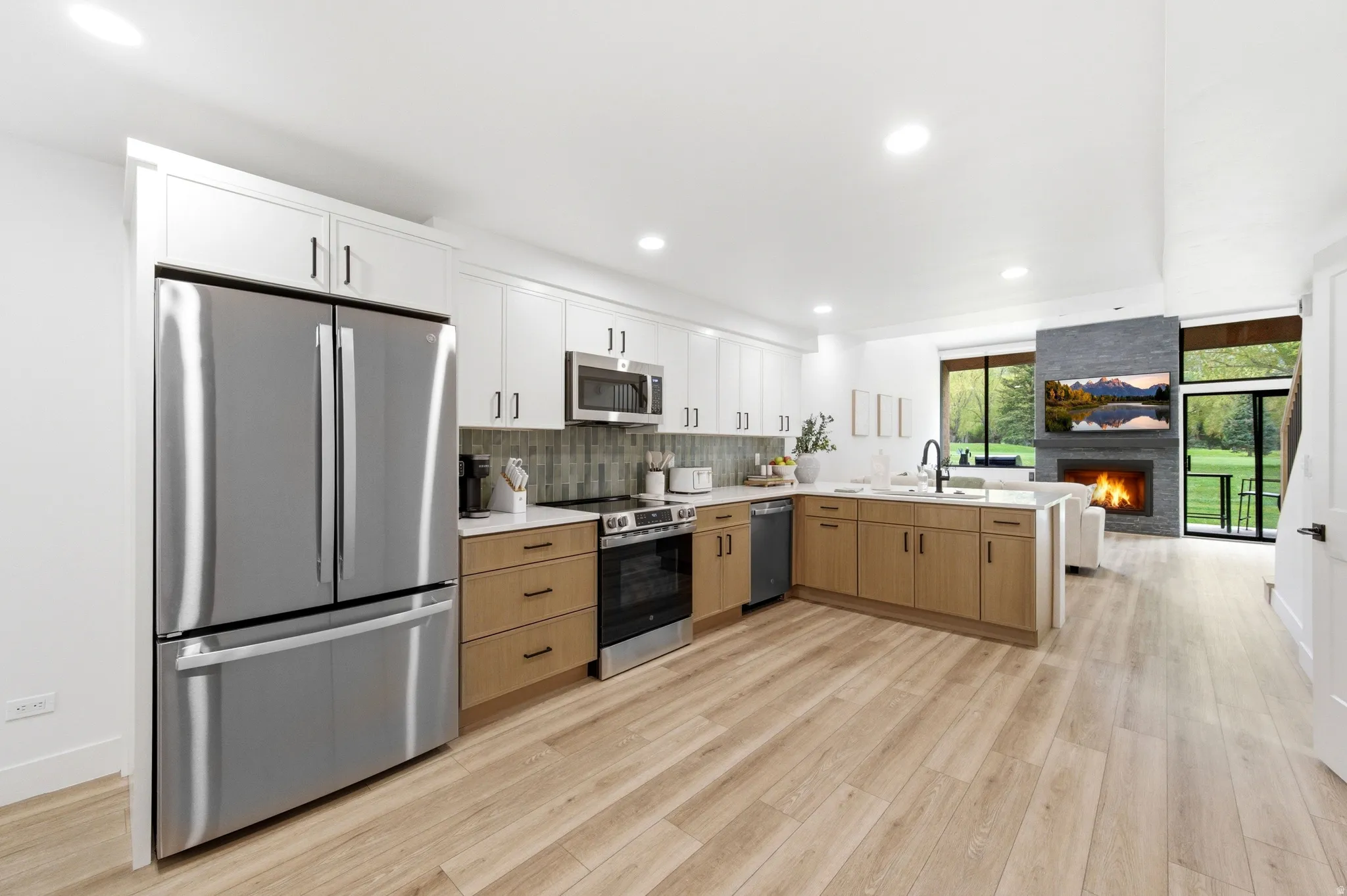 Modern kitchen featuring stainless steel appliances, two-tone cabinetry, and wood-finish flooring