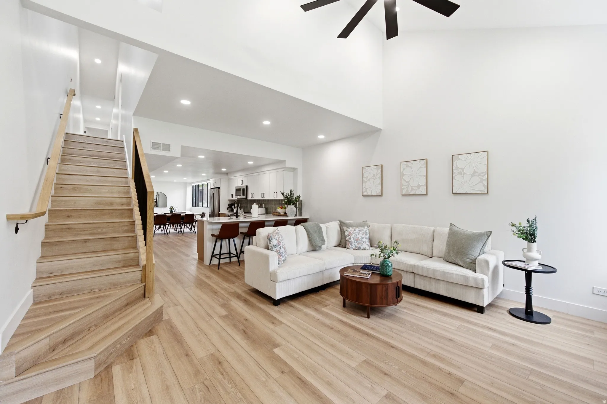 Open-concept living area with vaulted ceilings, wood-finish flooring, and a contemporary ceiling fan