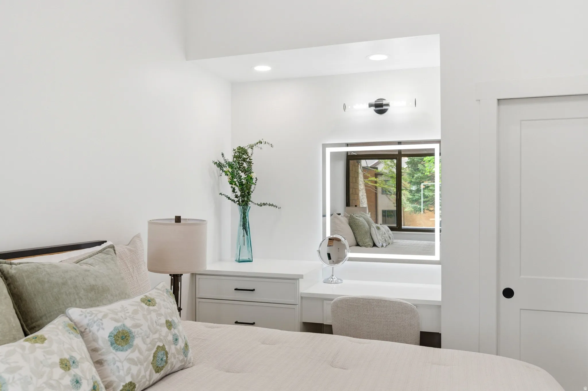 Recessed vanity area featuring a built-in illuminated mirror, dedicated task lighting, and a window seat