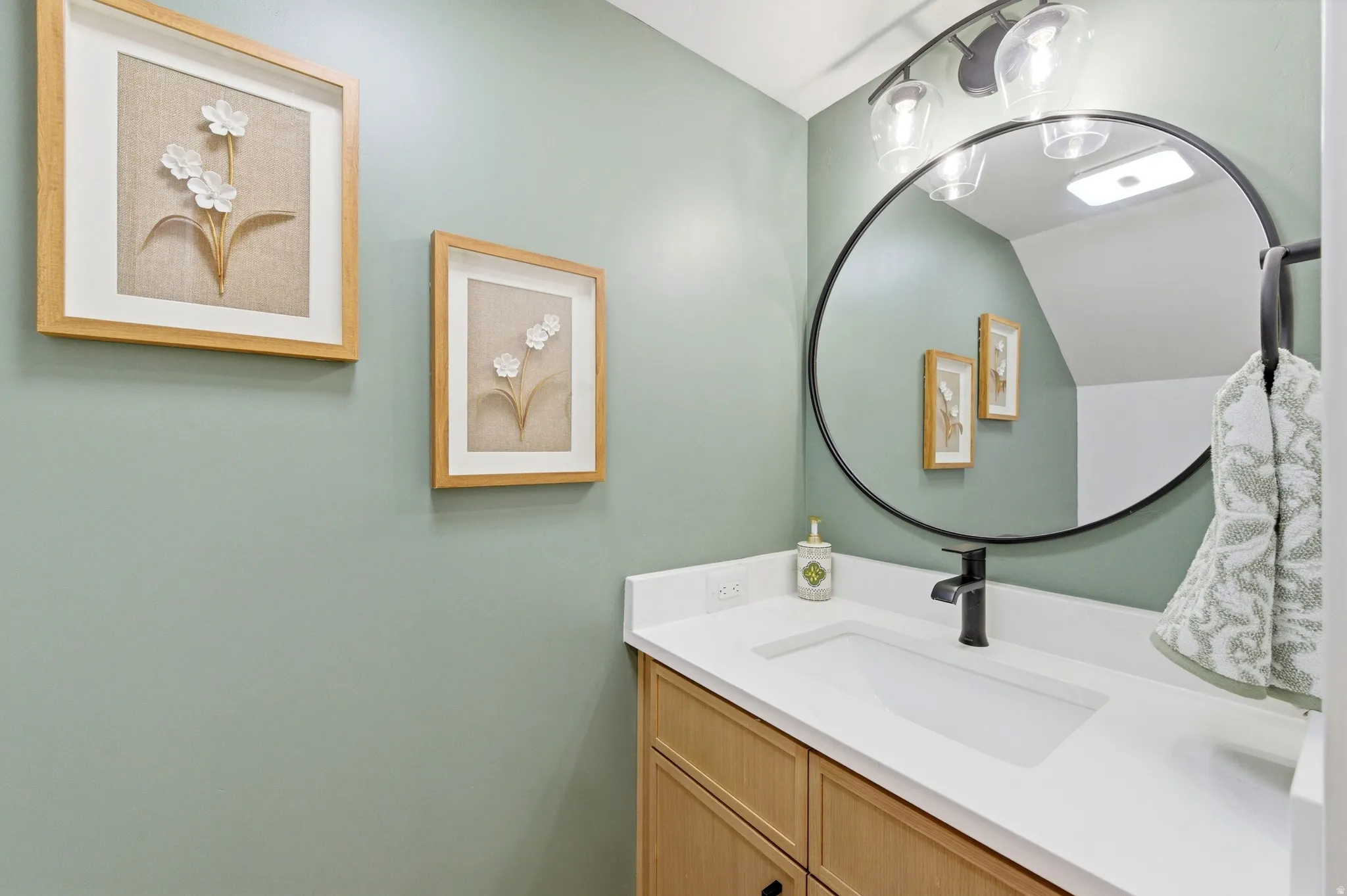 Bathroom vanity featuring a white countertop, undermount sink, and matte black faucet
