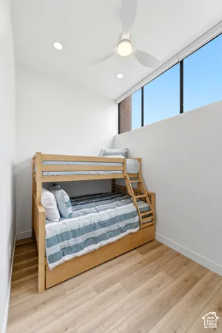 Recessed lighting, large windows, wood-finish flooring, white walls, and a ceiling fan with integrated lighting