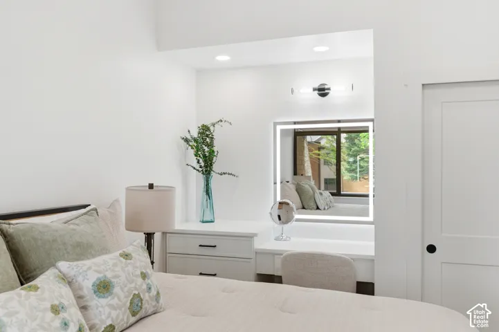 Recessed vanity area featuring an illuminated mirror, sconce lighting, and a window seat