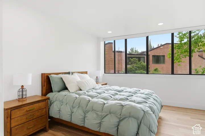 Wide window system with black frames, wood-finish flooring, white walls, and recessed lighting